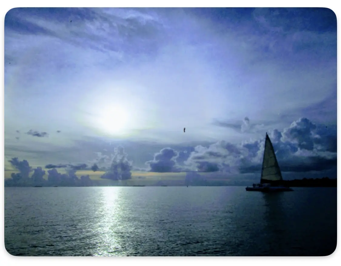 A sailboat is sailing on the ocean under cloudy skies.